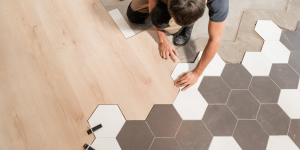 Man installing bathroom tile flooring - best bathroom designers in Oakville