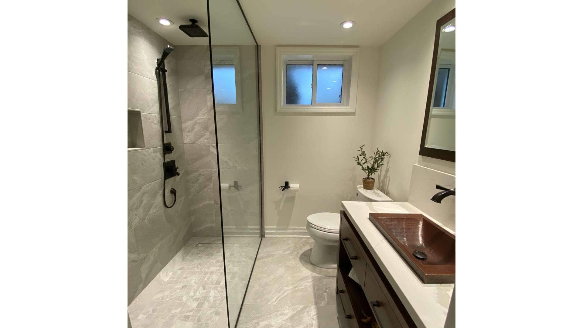 Modern basement bathroom renovation project with gray marble tiles and a standing shower with a shower niche